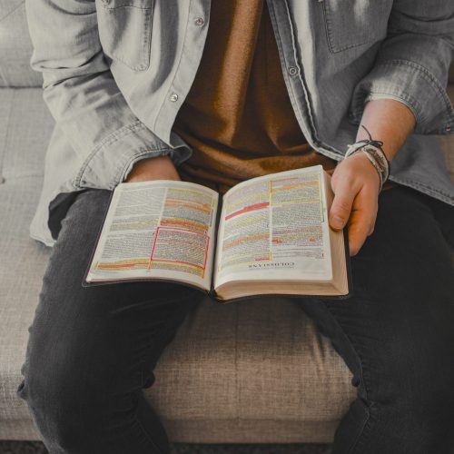 cropped photo of a person holding a Bible open on their lap